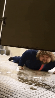a man in a suit and tie is crawling on the floor in a bathroom