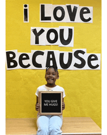 a young girl holds a sign that says you give me hugs