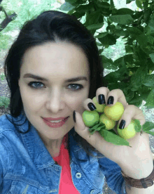 a woman in a denim jacket is holding a bunch of lemons