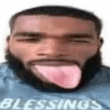 a man with a beard is sticking his tongue out and wearing a shirt that says blessings .