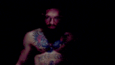 a man with a beard and a tattoo on his chest is smiling and making a funny face .