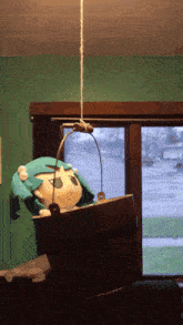 a stuffed animal is hanging from a rope in a bucket in front of a window