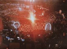 a crowd of people watching a concert with a sign that says ashtan on it