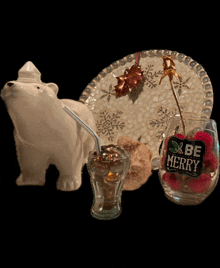 a glass that says be merry sits next to a polar bear figurine