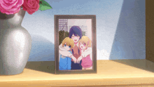 a framed picture of a woman and two children is on a shelf next to a vase of roses