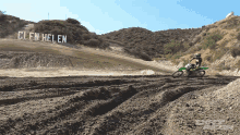 a person riding a dirt bike on a dirt track with a sign that says glen helen in the background