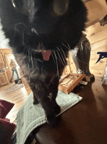 a black cat with its tongue hanging out standing on a table