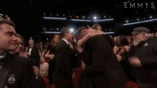 a man in a suit and bow tie is dancing in front of a crowd at an emmy awards ceremony .