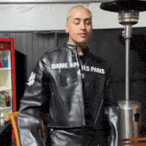 a man wearing a black leather jacket that says " dame apres paris "