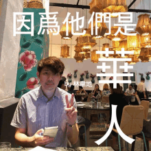 a man is sitting at a table in a restaurant with chinese writing on the wall behind him