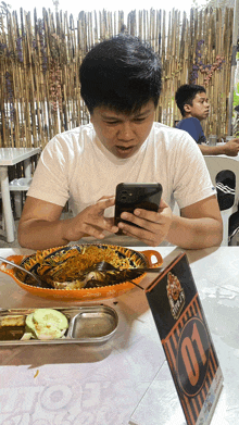 a man sits at a table with a plate of food looking at his phone