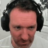 a man wearing headphones is making a funny face and looking at the camera .