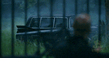 a black car with a red tail light is parked in a grassy field .
