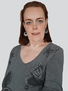 a woman wearing a gray shirt with a butterfly design on it