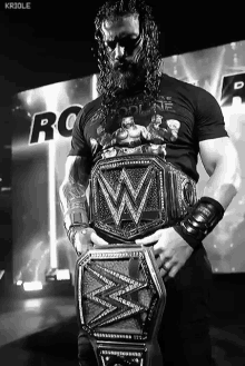 a black and white photo of a wrestler holding a wwe championship belt .