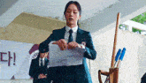 a woman in a suit and tie is holding a piece of paper in front of a microphone .