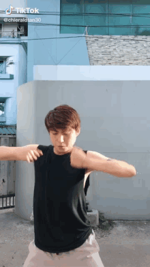 a man in a black tank top is dancing in front of a building