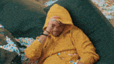 a man wearing a yellow hoodie is laying on a bean bag chair