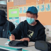 a boy wearing a mask sits at a desk in front of a wall that says " ajudante do dia "