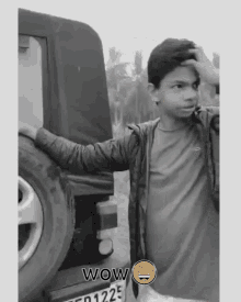 a black and white photo of a boy standing next to a car with the words wow written on the bottom