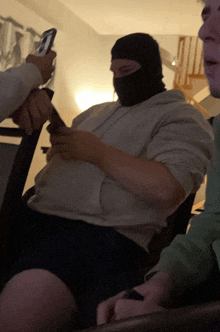 a man wearing a ski mask looks at a cell phone