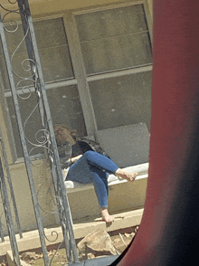 a woman sits barefoot on a bench outside a house