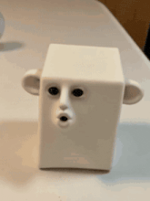 a white cube with a face on it is on a table