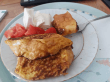 a plate of food with a slice of french toast and tomatoes on it