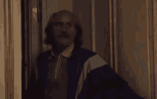 a man with a mustache and long hair is standing in a doorway .