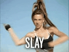 a woman in a bikini is standing in front of a blue sky with the word slay on her chest .