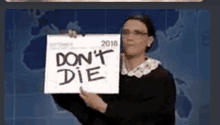 a woman is holding a sign that says don 't die .