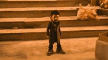 a small boy with a beard is standing in front of some stairs