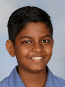 a young boy in a blue shirt smiles for a picture