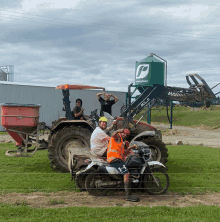 a man riding a motorcycle next to a tractor that says manpower