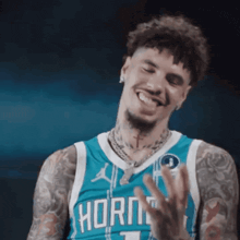 a man wearing a hornets jersey is smiling and waving his hand .