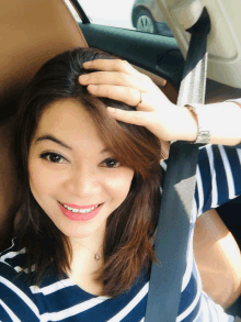 a woman in a blue and white striped shirt is sitting in a car