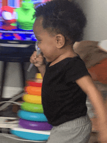 a toddler is playing with a toy stacker in front of a television