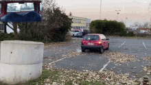 a red car is parked in a parking lot with leaves on the ground and the license plate says bnp ts