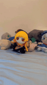 a stuffed animal with a yellow head sits on a bed with other stuffed animals