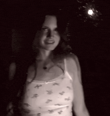 a woman wearing a white tank top with birds on it