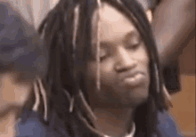 a man with dreadlocks is making a funny face while sitting in a courtroom .