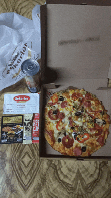 a can of soda sits next to a pizza in a cardboard box