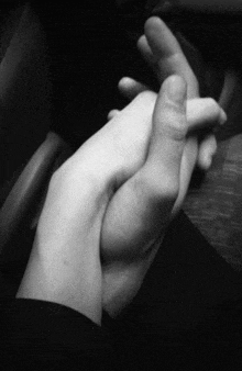 a man and woman are holding hands in a black and white photo .