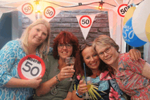 four women are posing for a picture with a sign that says moera 50