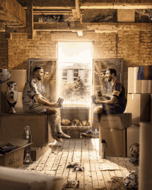 two soccer players are sitting on cardboard boxes in a room that says " messi goals "