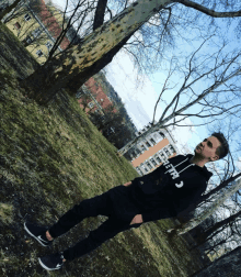 a young man wearing a black hoodie that says california is standing in a park