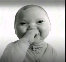 a baby is covering his mouth with his hand