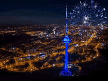 an aerial view of a city at night with a tower lit up in blue