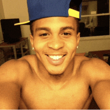 a shirtless man wearing a blue hat and smiling