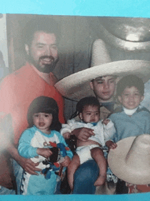 a man wearing a sombrero holds a baby in his lap